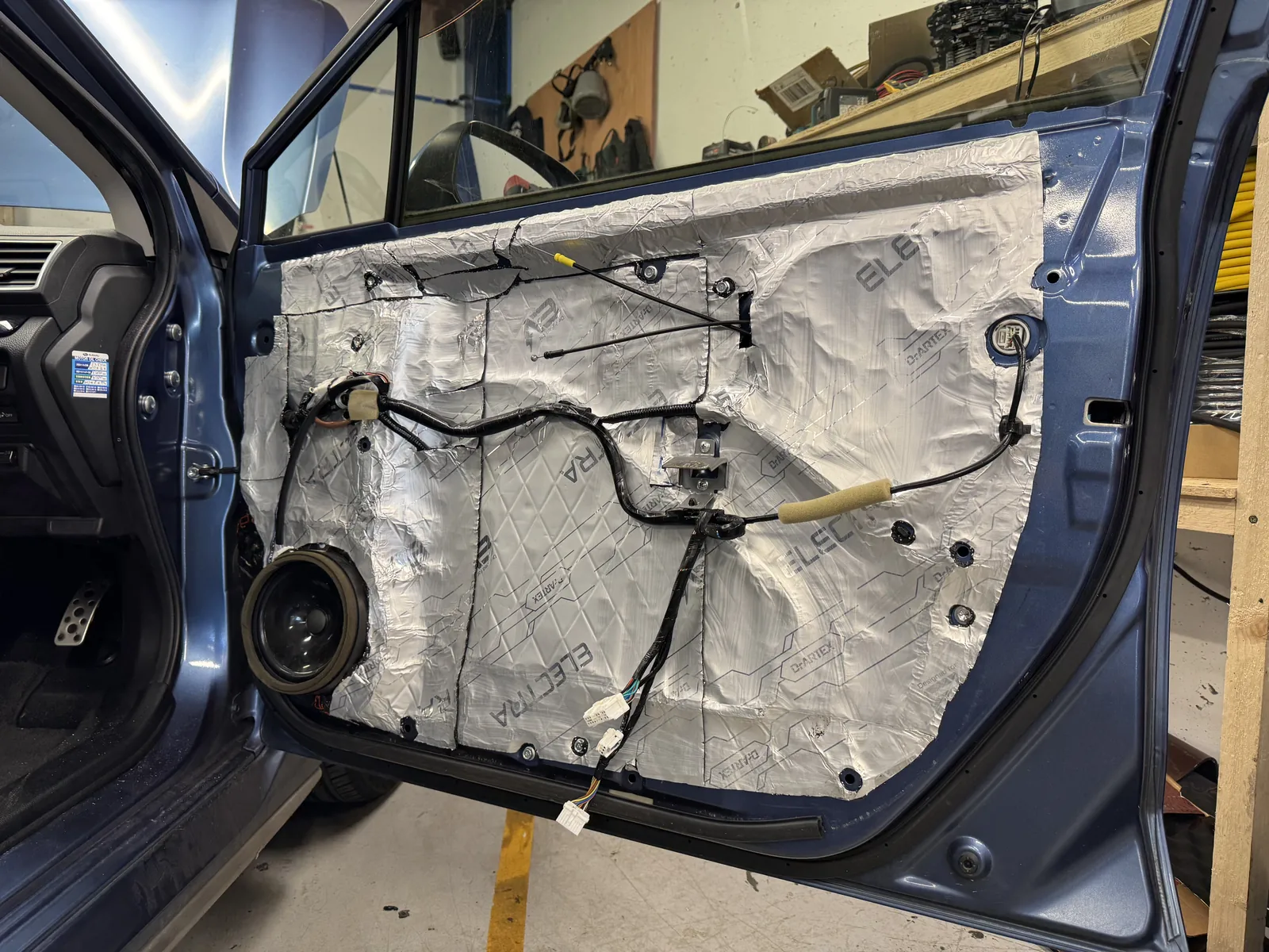 Subaru Impreza door panel removed showing speaker and insulation during audio upgrade